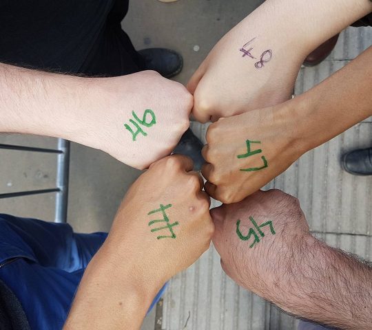 Communal experience of waiting in line at music venue Roundhouse in Camden, picture of five clenched fists with numbers on them from 44 to 48 outside a Radiohead gig.